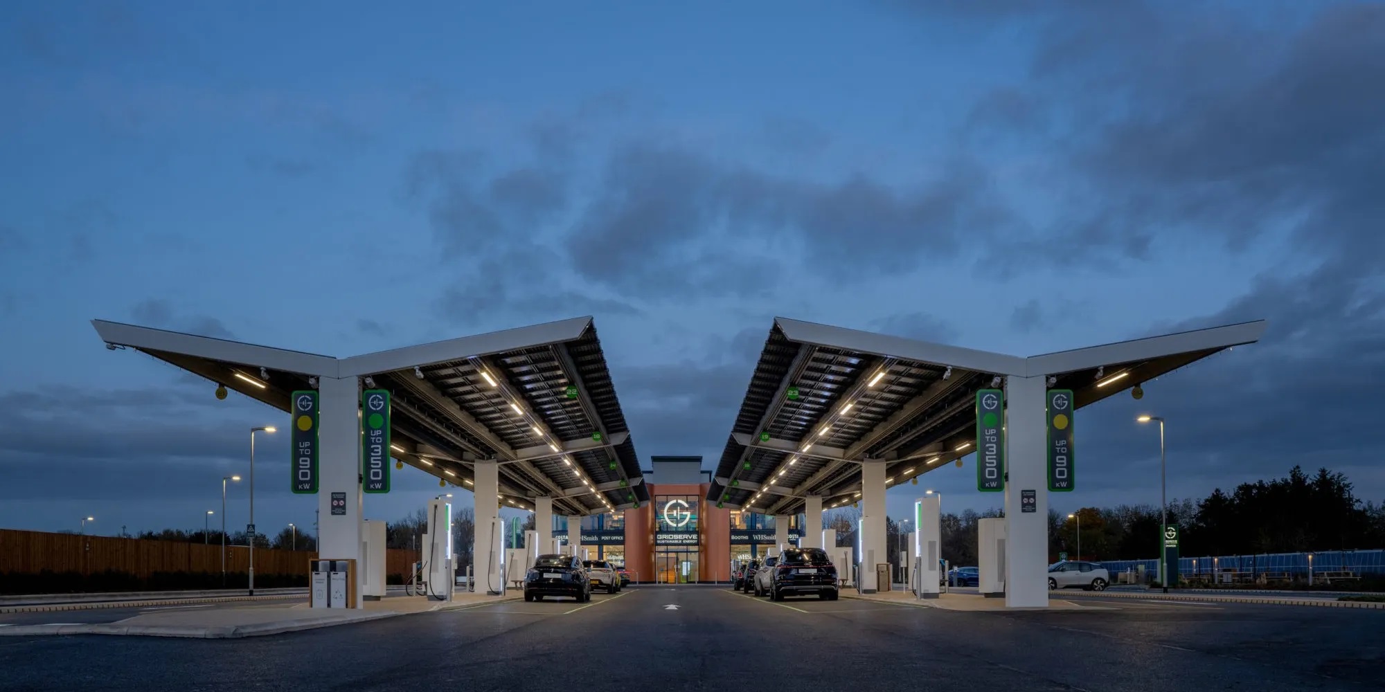 An outdoor parking structure featuring overhead bifacial solar panels and integrated EV charging pedestals for carbon-neutral mobility.