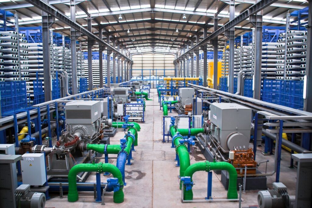 Vertical Francis turbine assembly inside a water power plant powerhouse, showing the generator shaft and wicket gate control system.