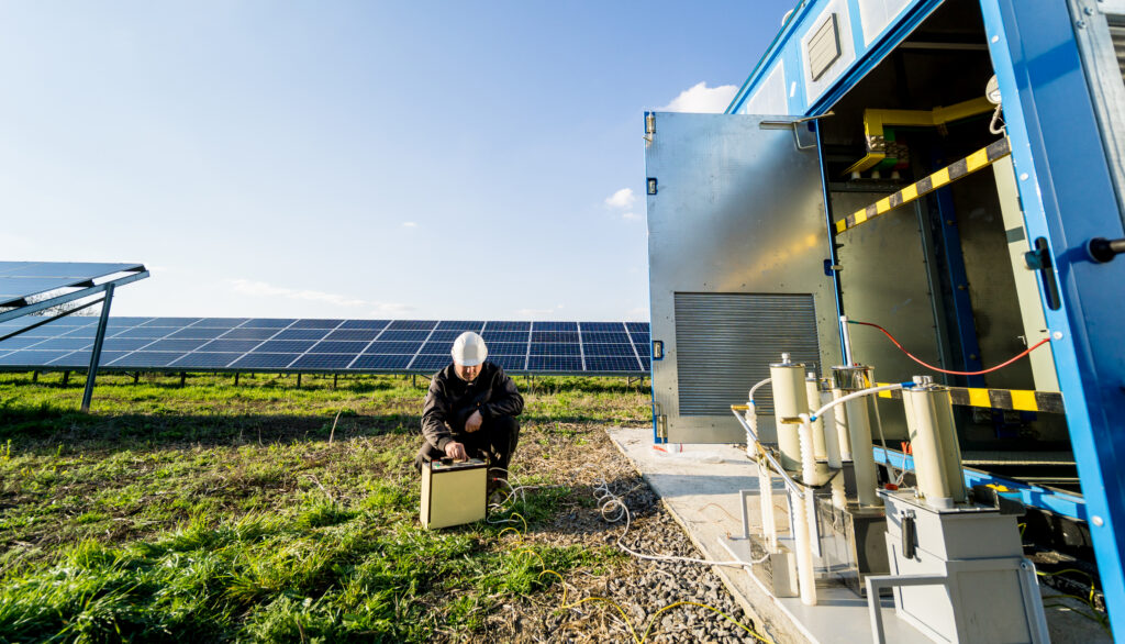 Hybrid renewable energy setup with a solar panel array connected to a containerized battery storage system and power inverters.