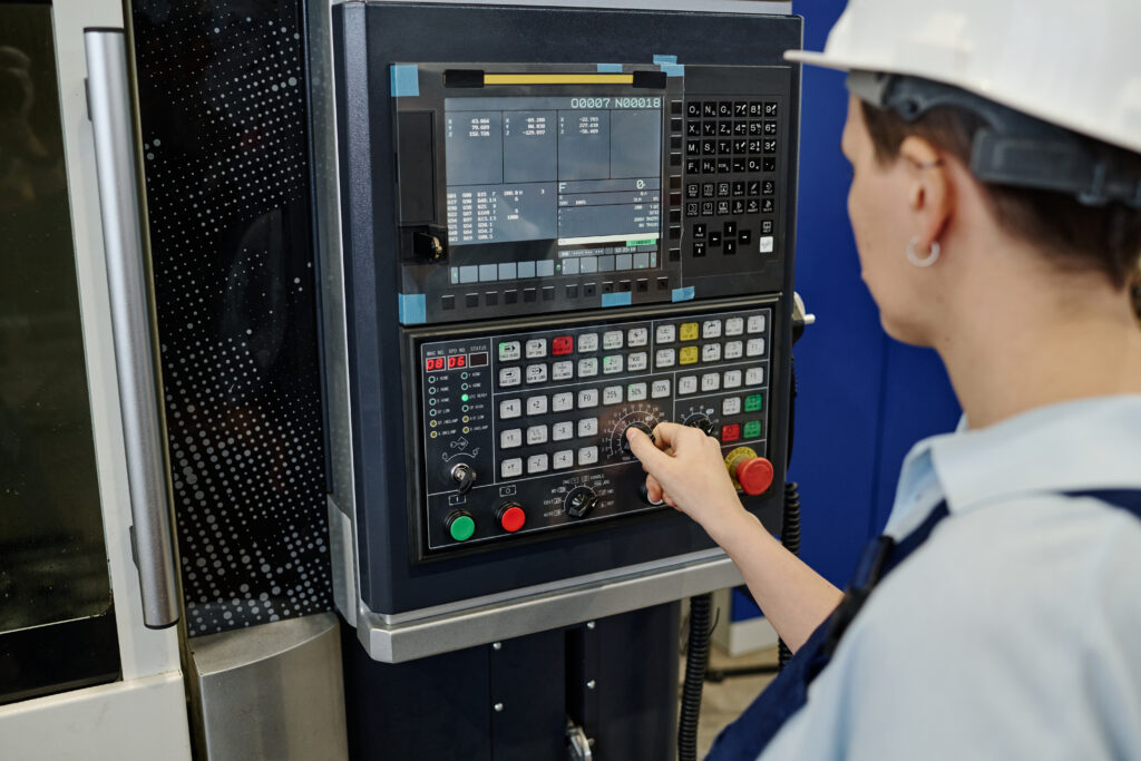 A technical worker in a control room monitoring a real-time automation dashboard and SCADA interface on a computer screen.