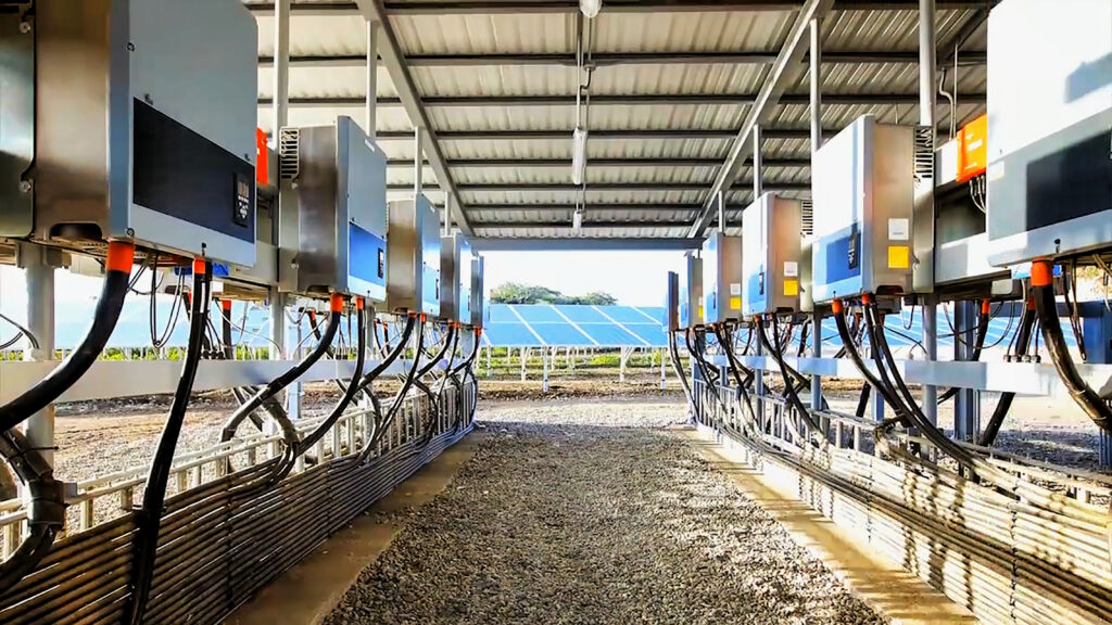 Hybrid renewable energy system showing solar panels connected to a containerized battery storage unit with integrated power inverters.