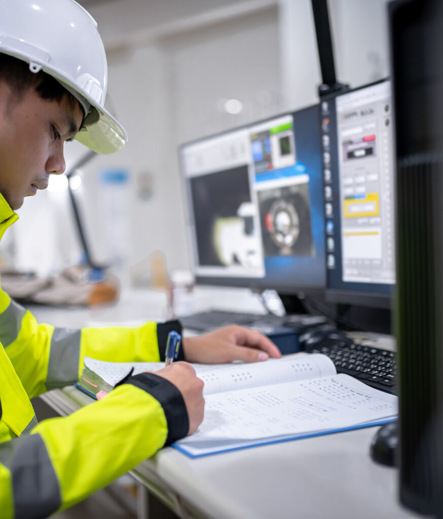 An industrial automation control room showing a SCADA software interface on multiple monitors for real-time monitoring of factory processes.