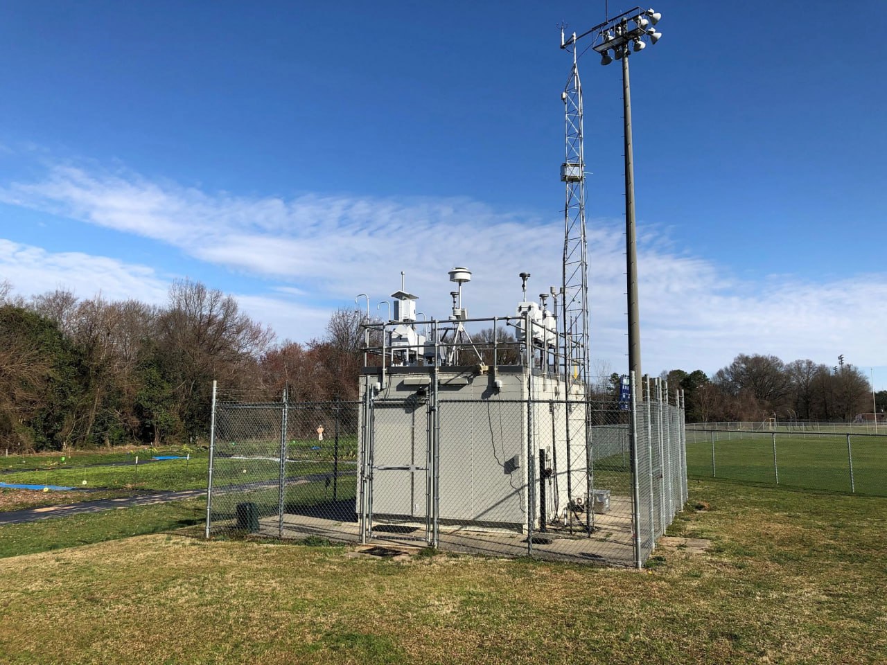 Professional automated meteorological station measuring wind speed and temperature in a grassy field.